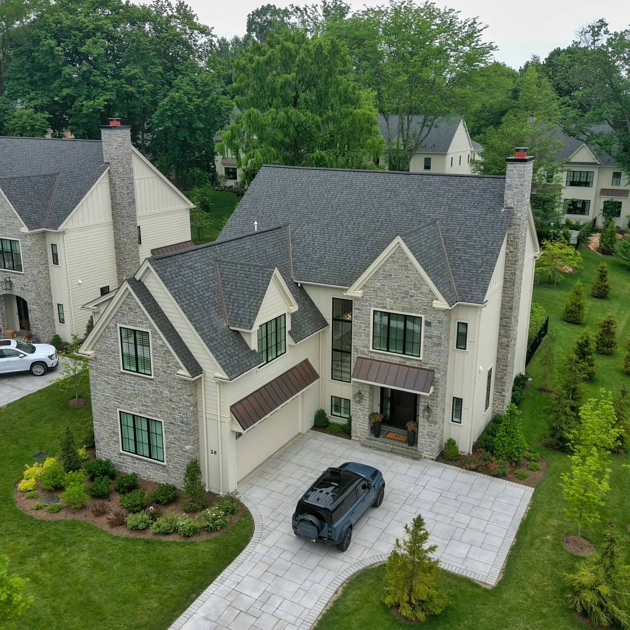 Aerial view of a newer stone and clapboard home with a steep gabled roof and copper awnings during a ValueGuard home inspection in Wayne on the Main Line