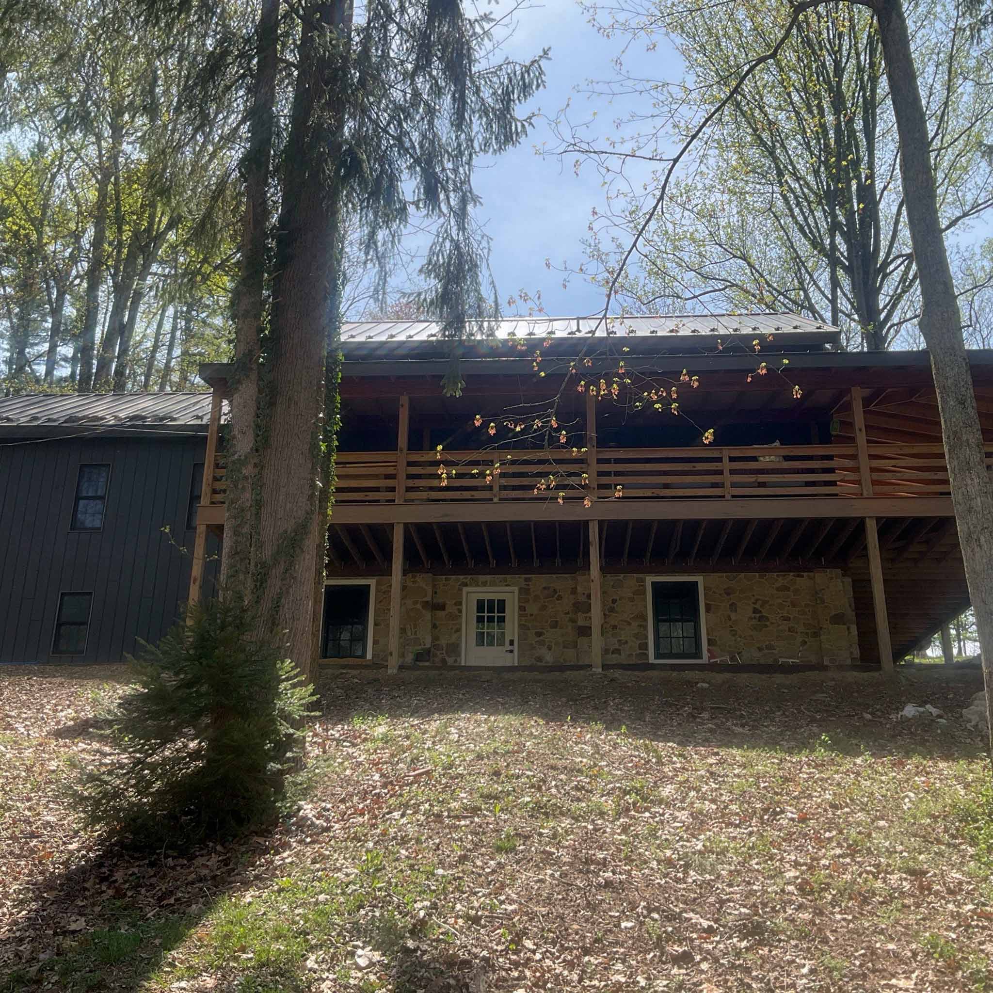 West Chester Home Inspection — Historic Stone Home Historic stone home with a two-level wood deck and a standing-seam metal roof set on a wooded lot in West Chester, Chester County PA, inspected by ValueGuard home inspectors