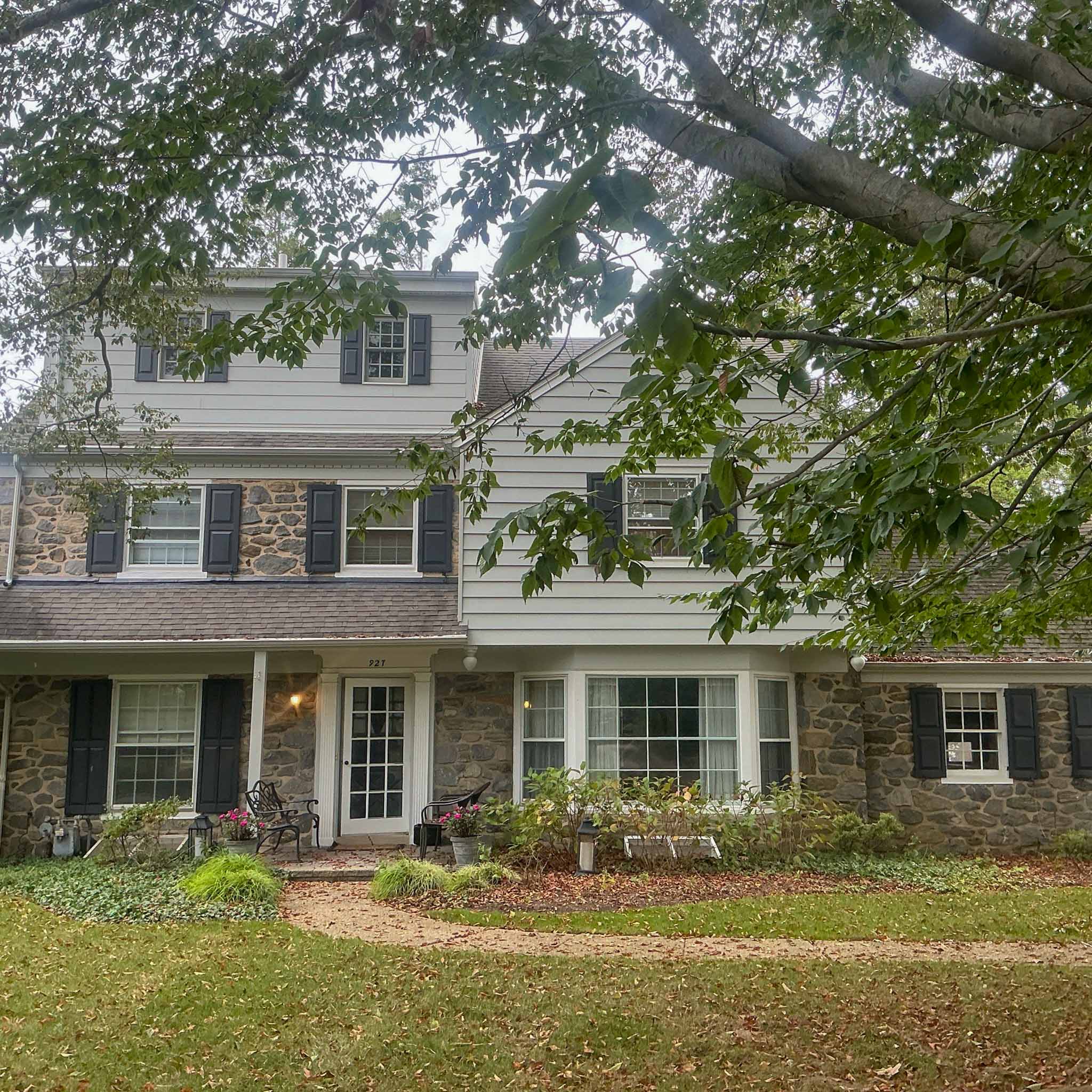 Mid-century stone-and-clapboard colonial with black shutters and a bay window in Wynnewood inspected by ValueGuard