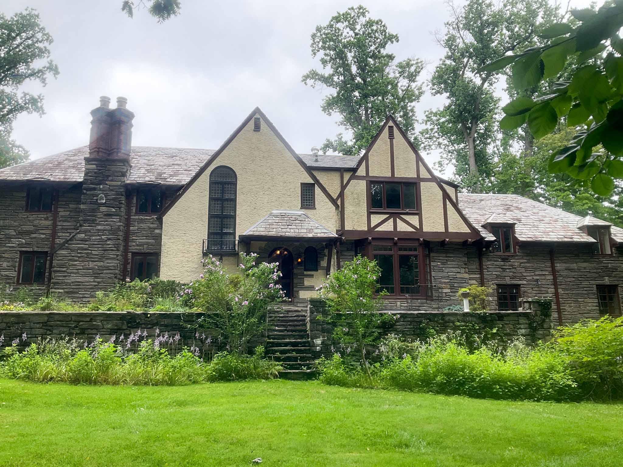 1927 stone and stucco Tudor Revival home in Wynnewood PA with slate roof, half-timbering, and massive masonry chimney, inspected by ValueGuard